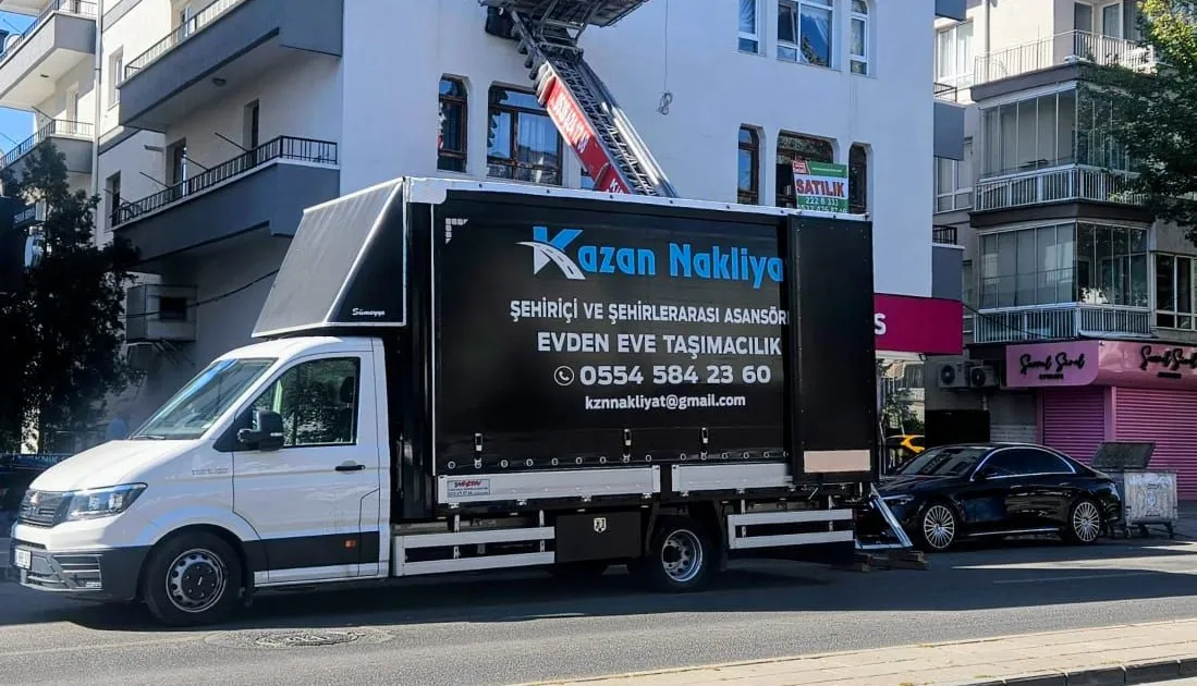 Mobil asansörle eşya taşınan binanın önünde Kazan Nakliyat kamyonu
